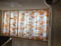 Large illuminated salt stone wall panels with a warm orange and cream marbled pattern, installed in an interior space.